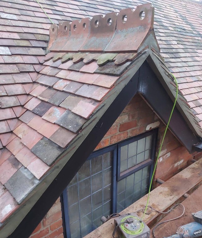 Decorative ridge tiles on a gable end during the final stage of a re-roof