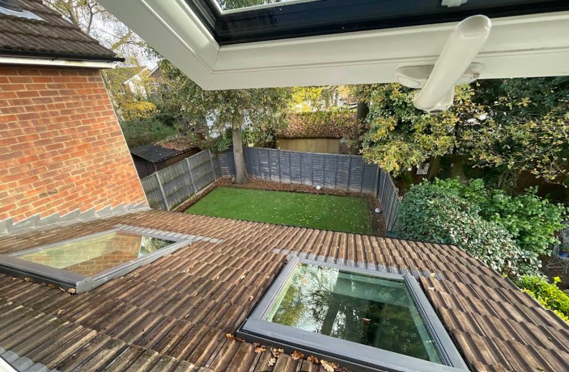 View through a new flat roof skylight over the tiled roof and garden below