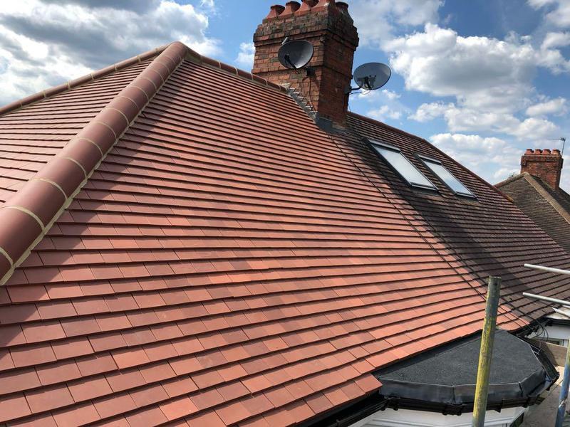 New red tiled roof with dry ridge caps and two roof windows after a full re-roof