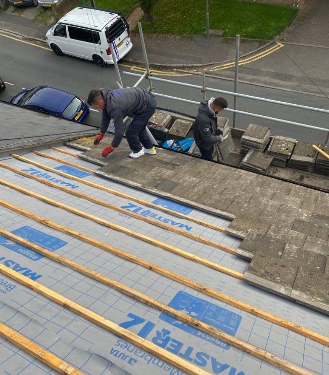 H Lee & Son roofers inspecting and stripping a tiled roof from scaffolding during a survey