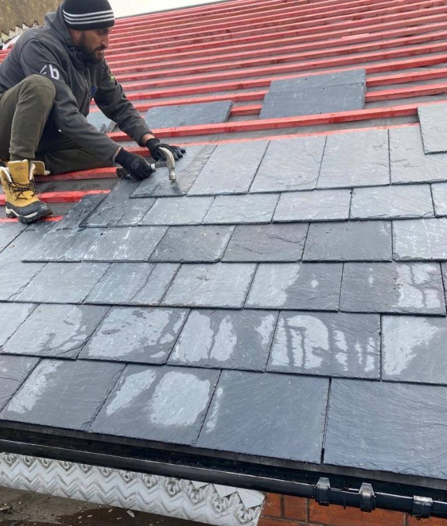 H Lee & Son roofer replacing slipped slate tiles during a roof repair in Berkshire