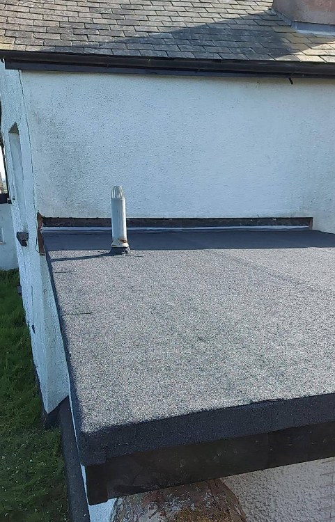 Completed grey felt flat roof detailed around a vent pipe