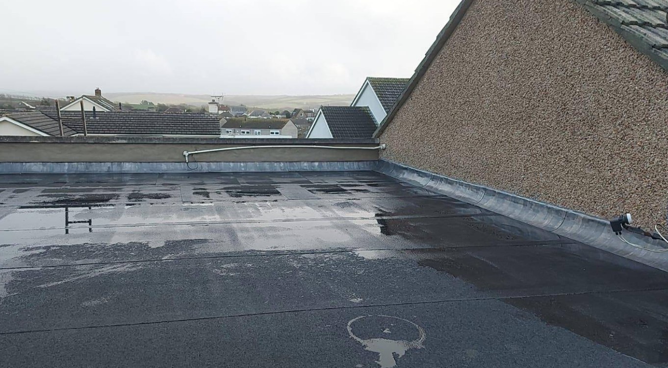 Flat roof surface finished around drainage outlet and perimeter edge trim
